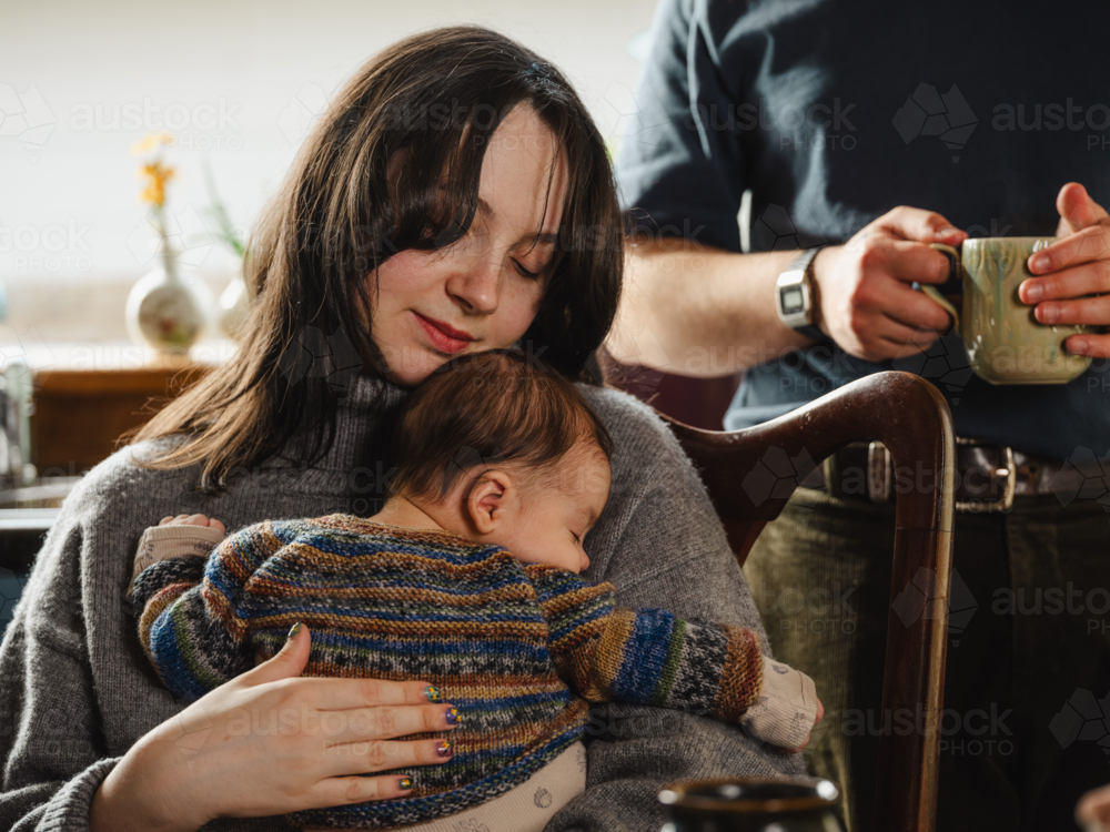 Young mother holding baby dressed in striped sweater - Australian Stock Image