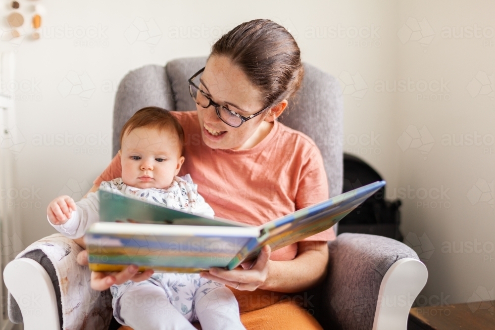 Young mother together with baby reading a picture book - Australian Stock Image