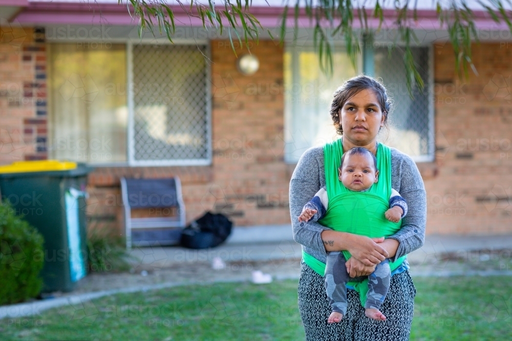 Young mother with baby in wrap out front of their home - Australian Stock Image