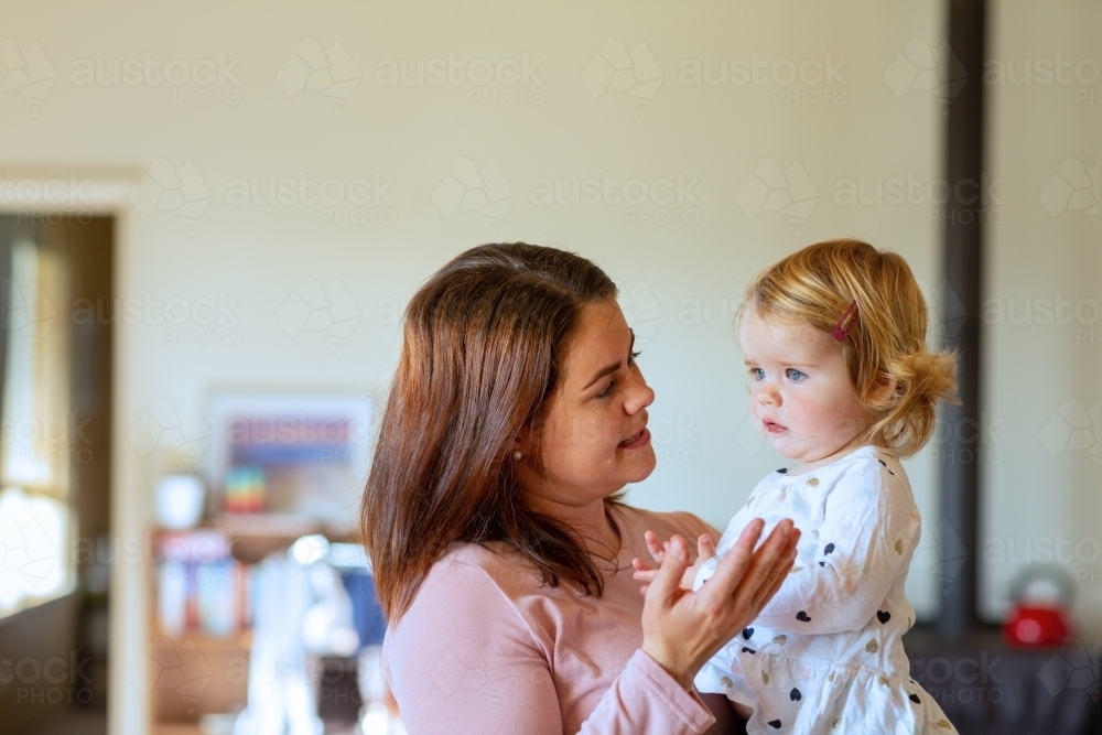 young mum holding toddler and talking to her - Australian Stock Image