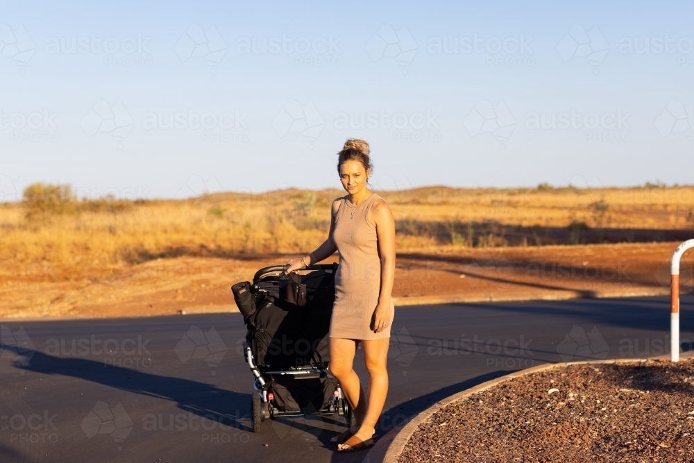 young mum with stroller on side of street in the Pilbara - Australian Stock Image