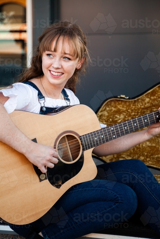 Young musician playing her guitar busking - Australian Stock Image
