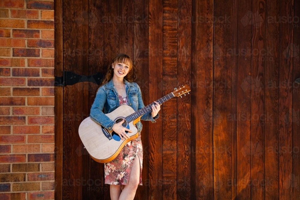 Young musician standing against solid wooden doors - Australian Stock Image