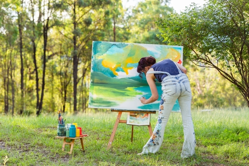 Young painter in overalls painting picture - Australian Stock Image