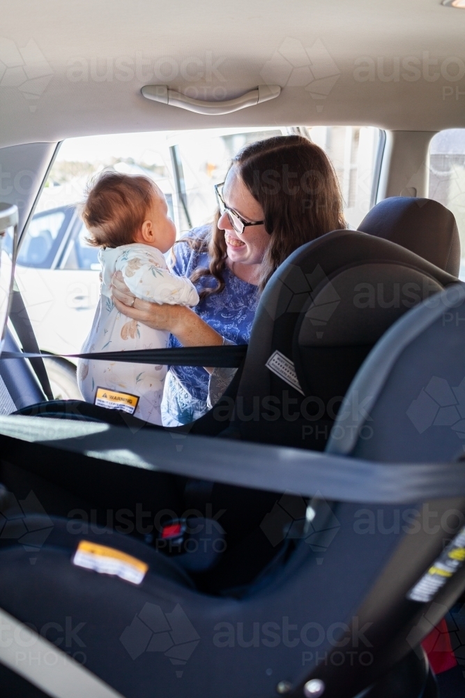 Image of Young parent lifting baby out of rear facing child car seat