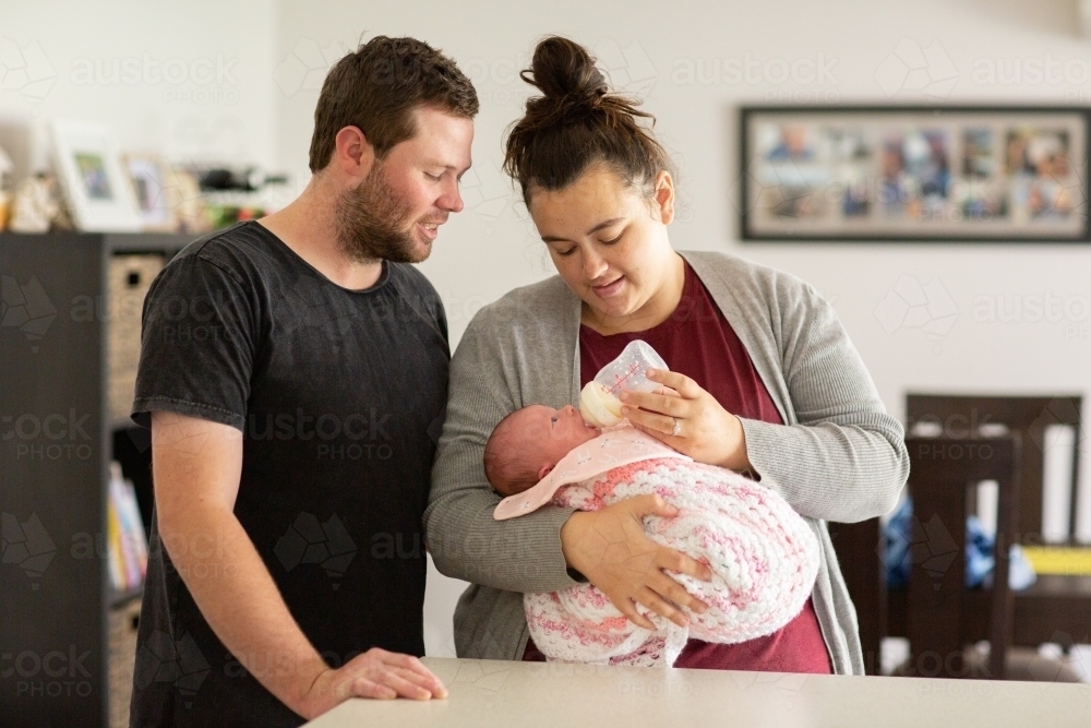 Young parents feeding newborn baby with baby bottle - Australian Stock Image