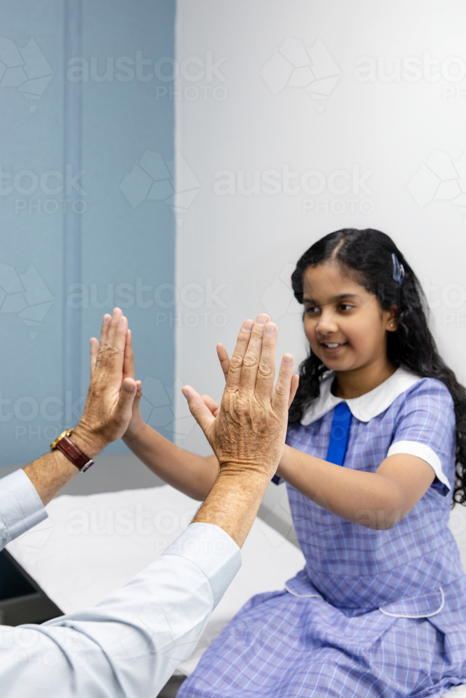 Young patient high-fiving doctor in office - Australian Stock Image