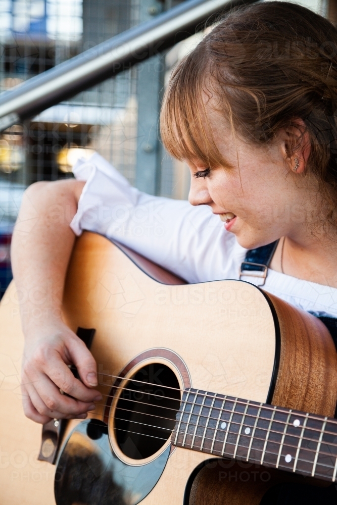 Young person playing guitar outside cafe - Australian Stock Image