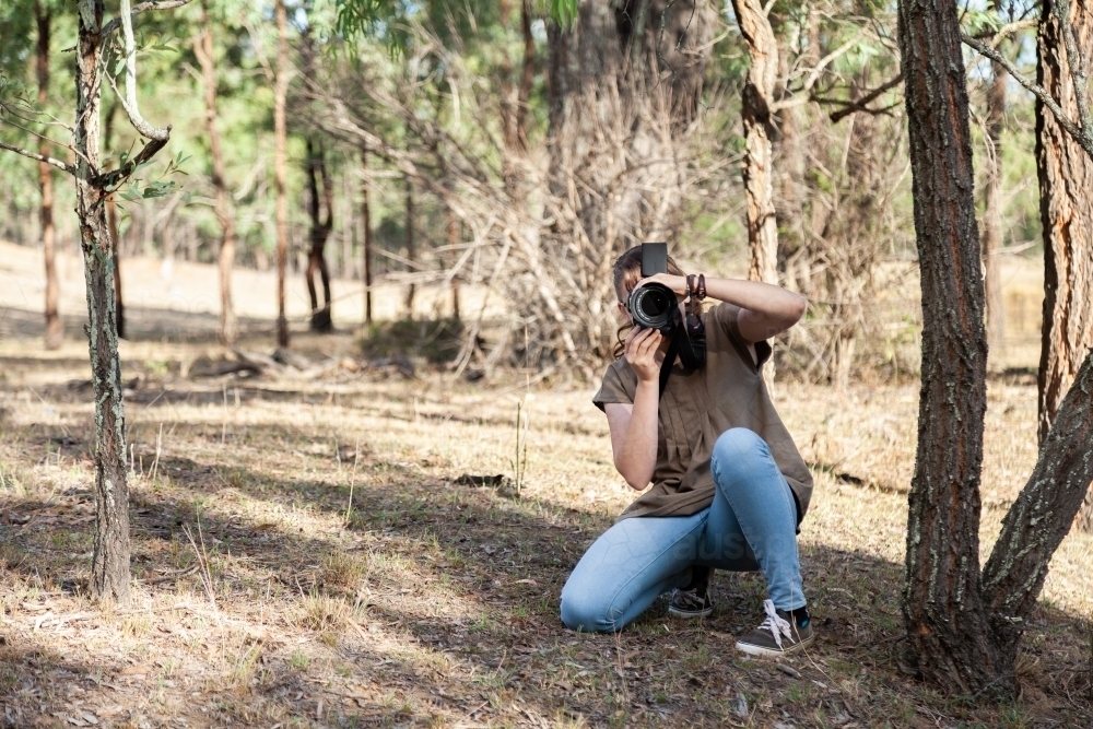 Young photographer outdoors taking a photo - Australian Stock Image