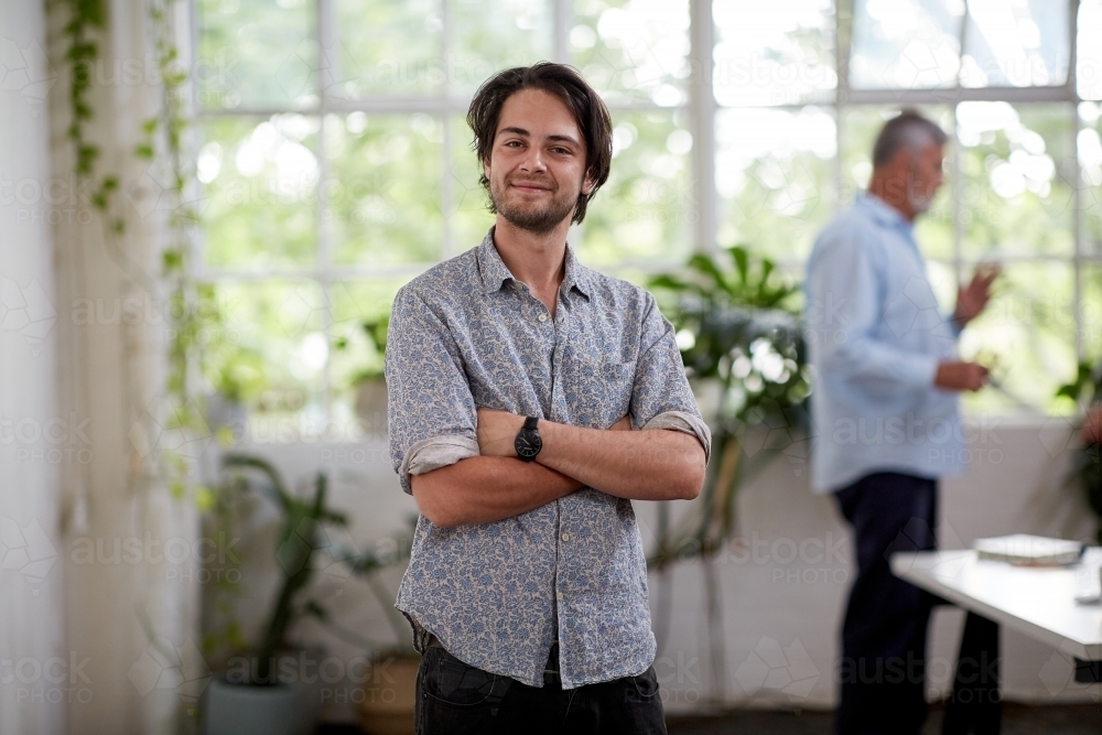 Young professional man standing in an open plan office - Australian Stock Image