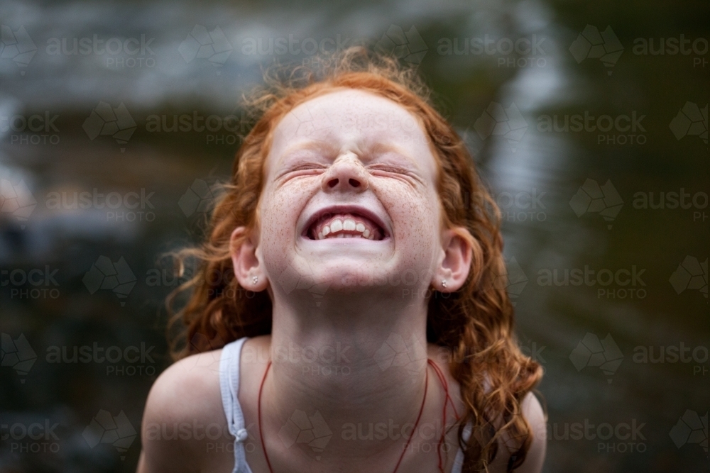 Young redhead girl laughing by the riverside - Australian Stock Image