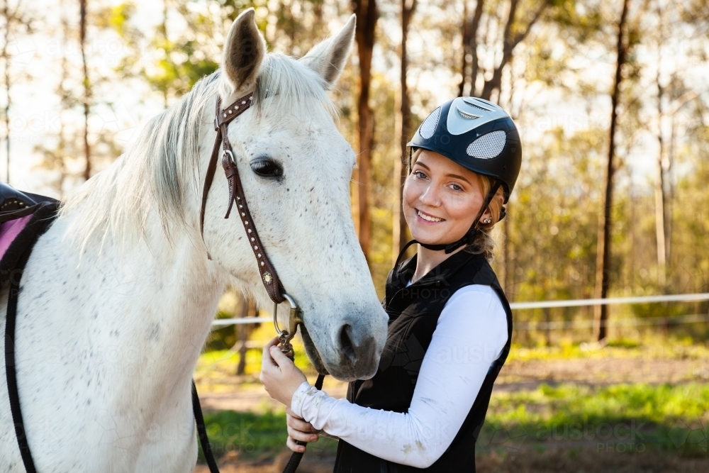 Young rider wearing a horse riding helmet while with her pet horse - Australian Stock Image