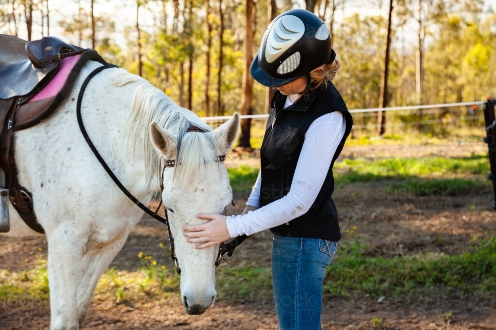 Young rider wearing a horse riding helmet while with her pet horse - Australian Stock Image