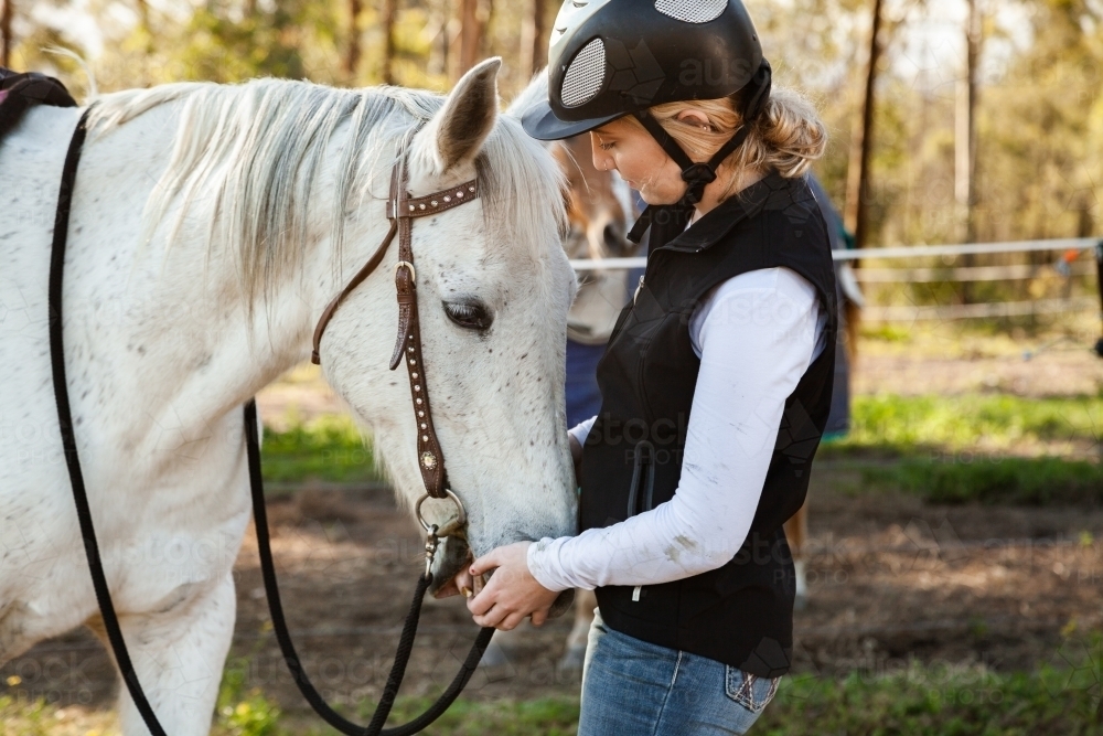 Young rider wearing a horse riding helmet while with her pet horse - Australian Stock Image