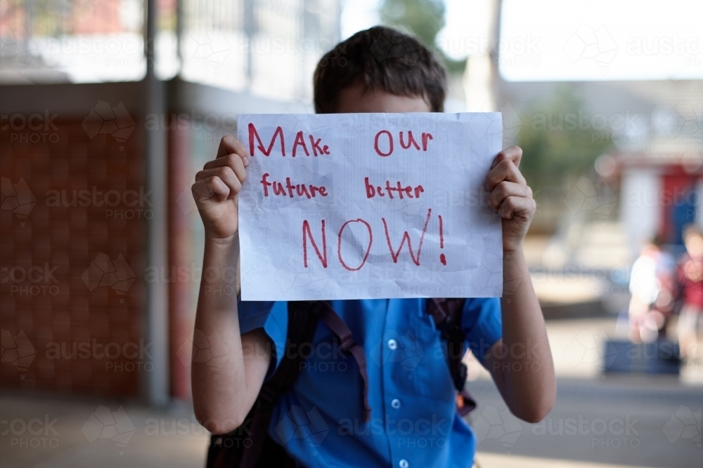 Young school boy holding up message on paper - Australian Stock Image