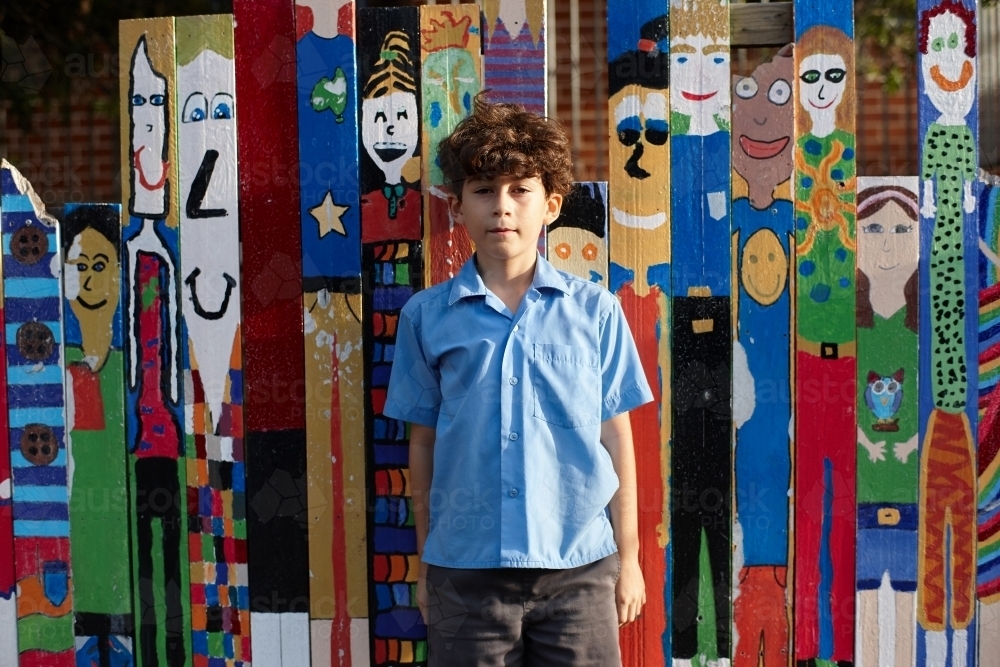 Young school boy in front of colourful paintings at school - Australian Stock Image