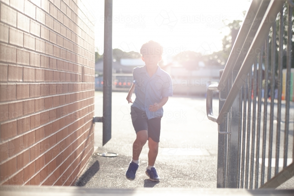 Young school boy running towards stairs at school - Australian Stock Image