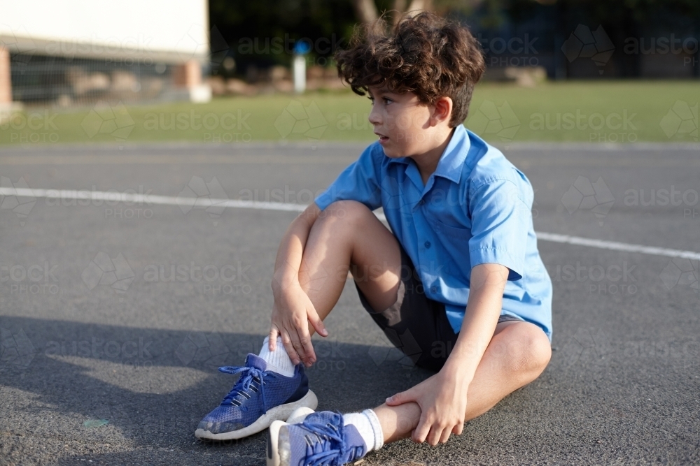 Young school boy seated outdoors at playground - Australian Stock Image