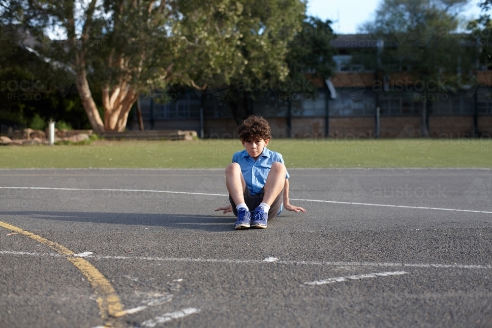 Young school boy seated outdoors at school grounds - Australian Stock Image