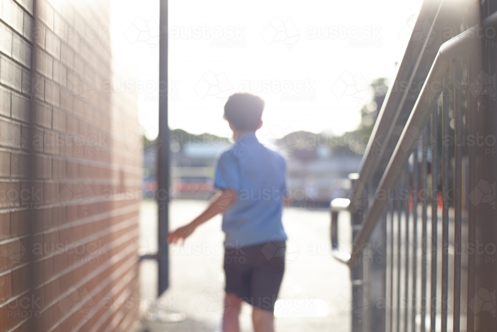 Young school boy walking away from stairs at school playground - Australian Stock Image