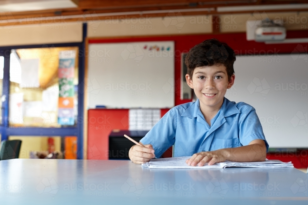 Young school boy writing in classroom - Australian Stock Image