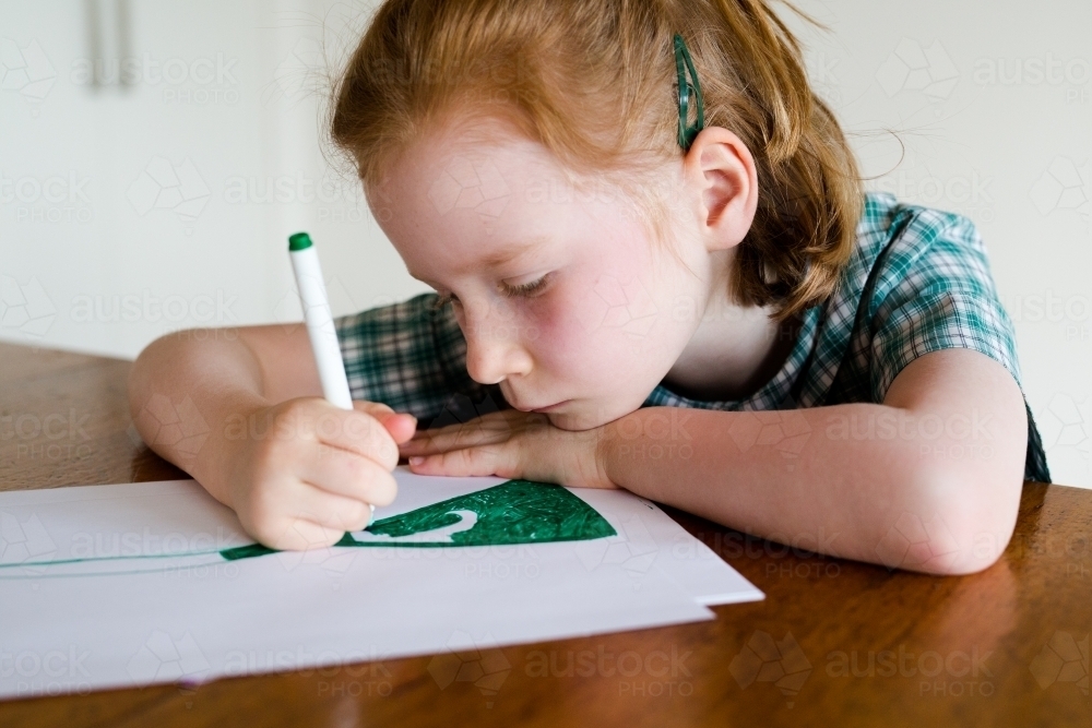 Young school girl drawing at a desk - Australian Stock Image