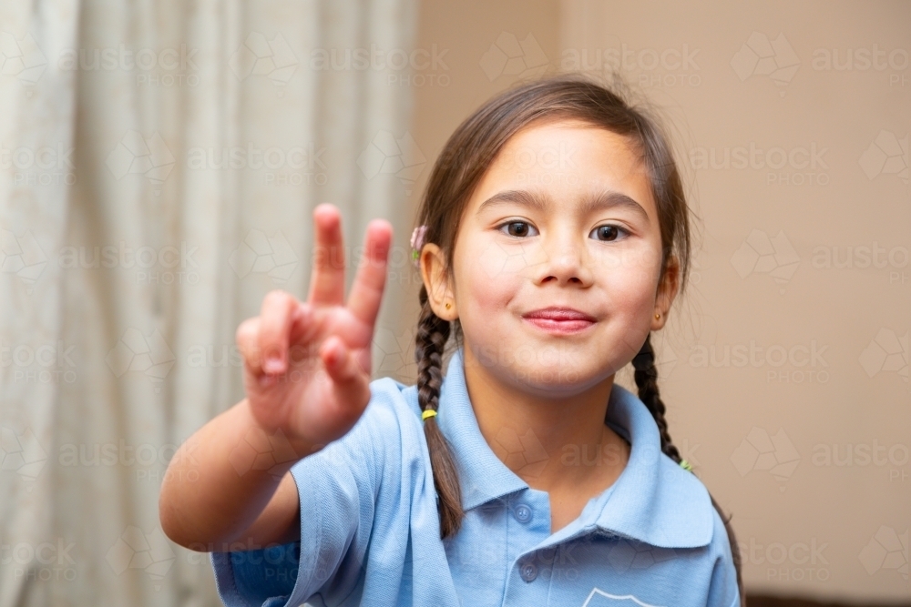 Young school girl giving "peace" sign - Australian Stock Image
