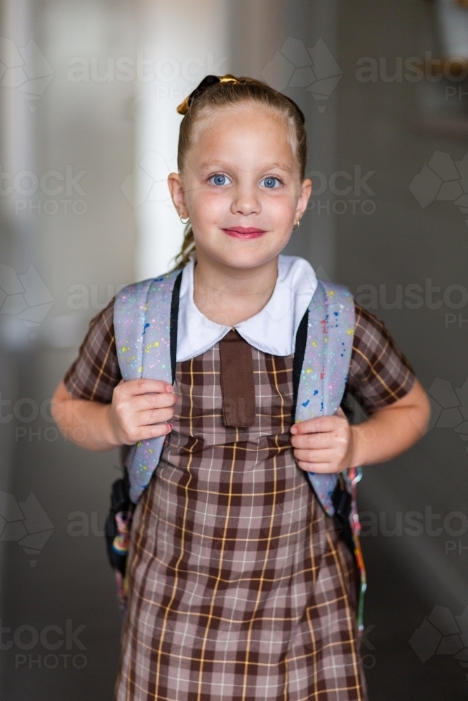 Young school girl in hallway with bag looking at camera - Australian Stock Image