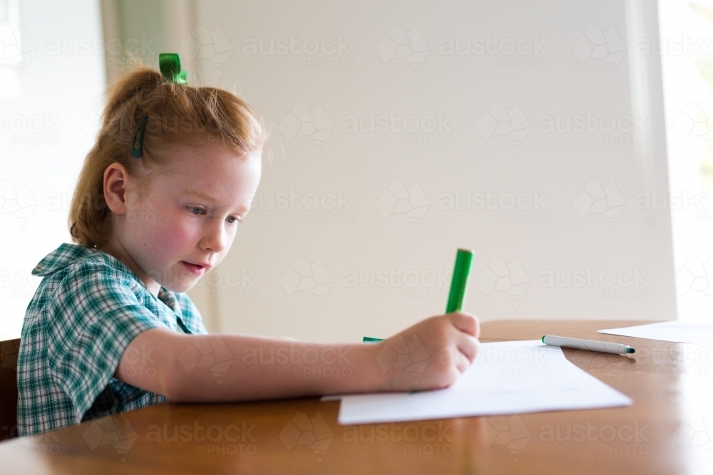Image of Young school girl sitting at a desk writing and drawing ...