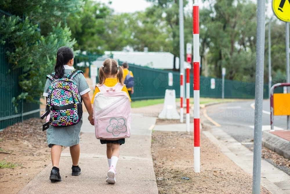 Young school kids walking along footpath with bags on - Australian Stock Image