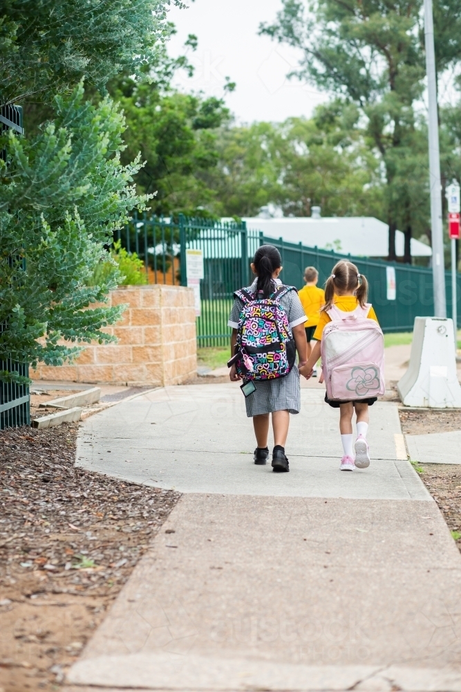 Young school kids walking along footpath with bags on - Australian Stock Image