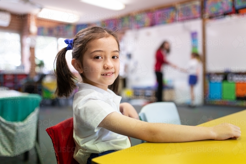 Image of Young Schoolgirl in Classroom Smiling at Camera - Austockphoto