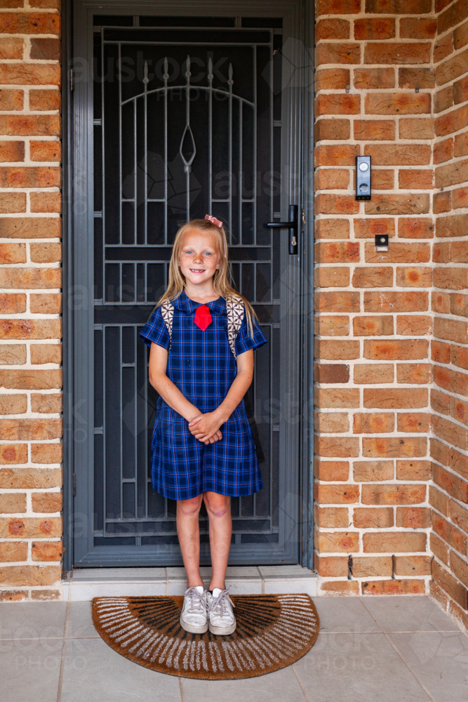 Image of Young schoolgirl ready for primary school by front door of ...