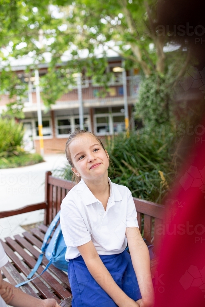 Young Schoolgirl Sitting Outside Smiling - Australian Stock Image