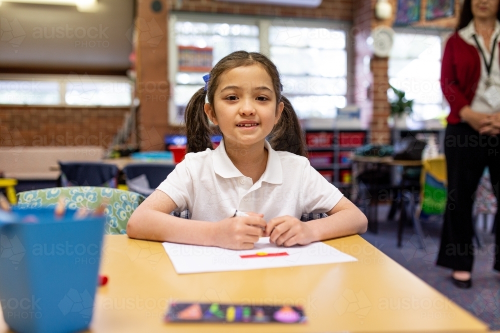 Image of Young Schoolgirl Smiling at Camera in Classroom - Austockphoto