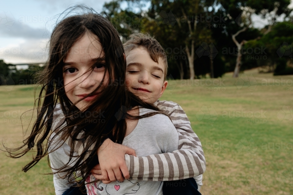 Young sister gives her younger brother a piggy back ride - Australian Stock Image