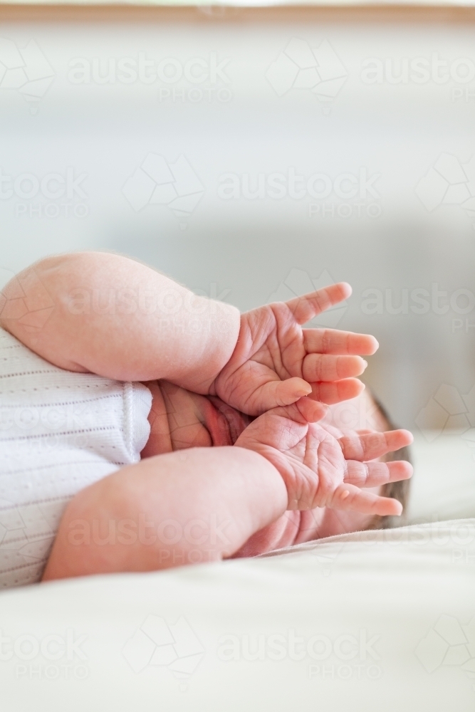 Young sleepy baby rubbing eyes with hands - Australian Stock Image