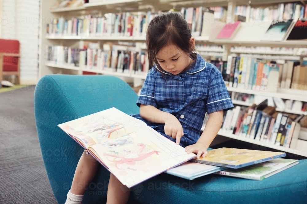 Young student girl reading in library - Australian Stock Image