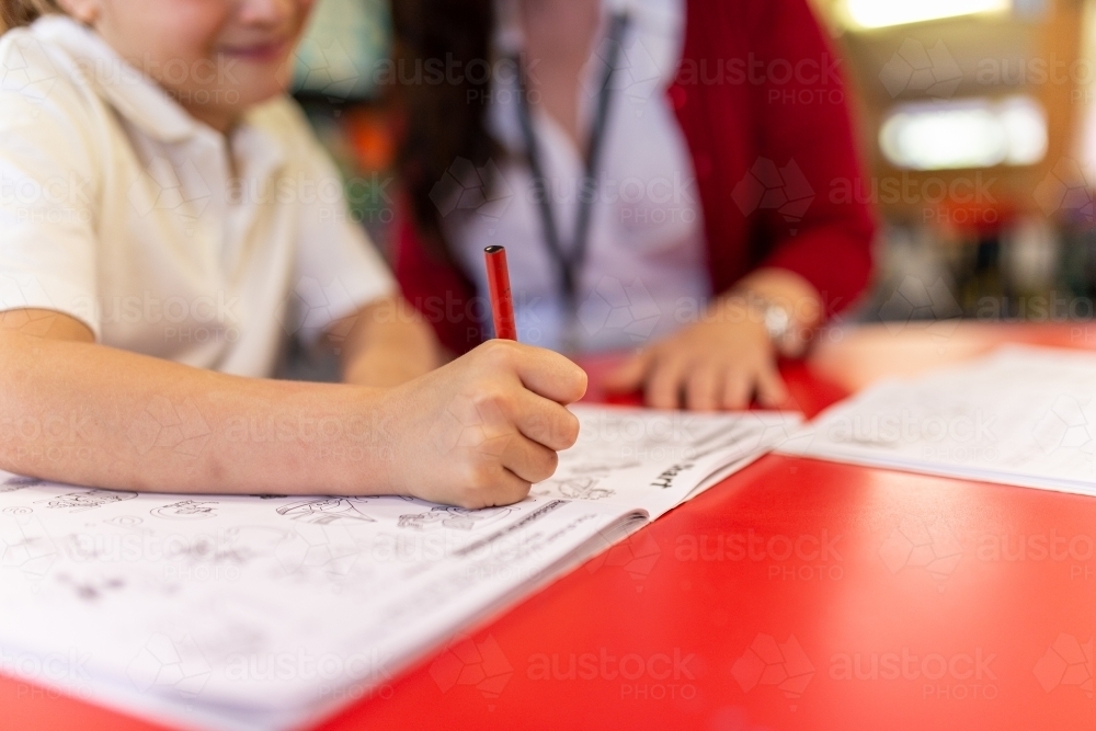 Image of Young Student Writing in Workbook - Austockphoto