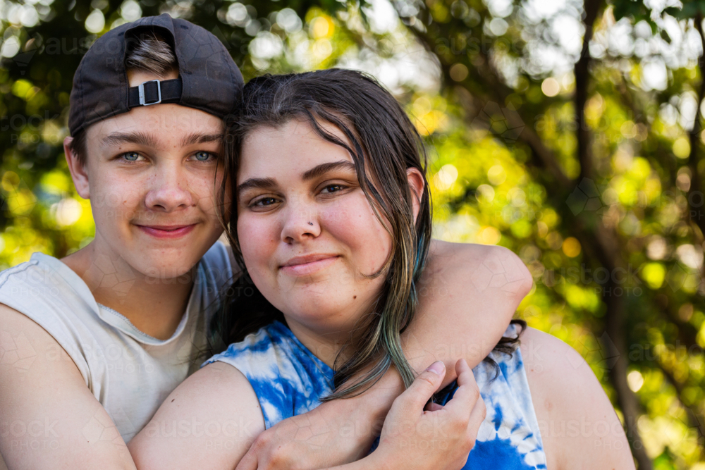 Young teen aboriginal Australian kids hugging one another outdoors - Australian Stock Image
