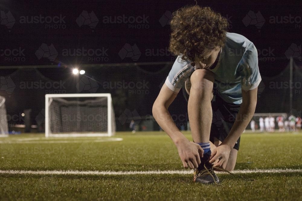 Young teen boy preparing to do evening soccer training - Australian Stock Image