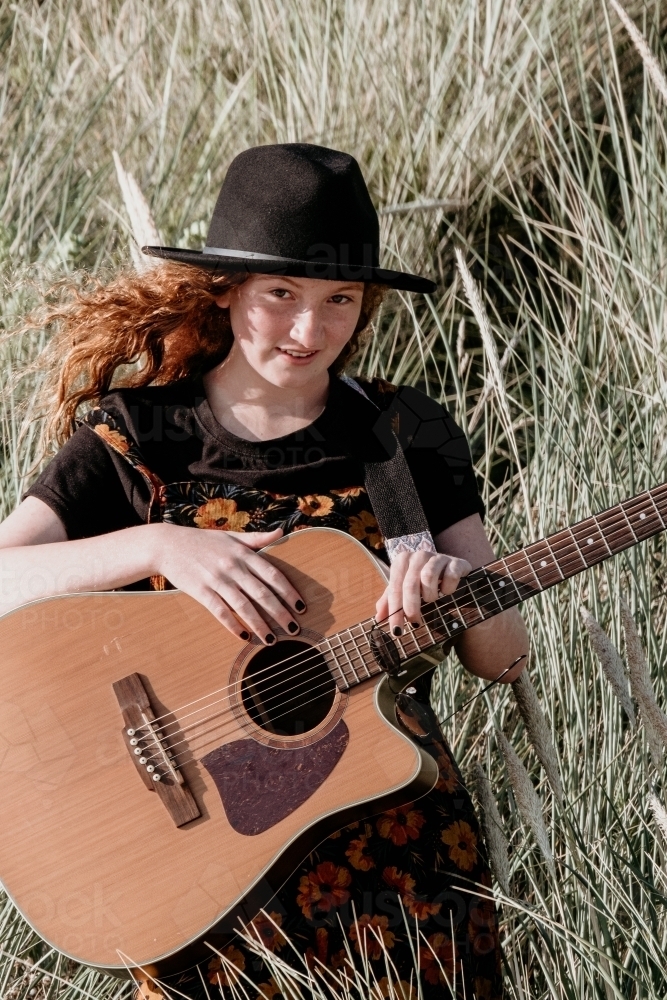 Young teen girl smiles and has her guitar. - Australian Stock Image