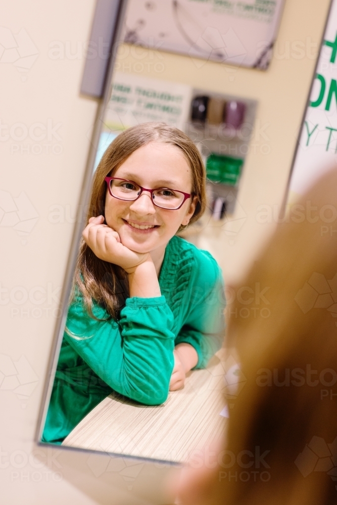 young teen girl trying on new glasses - Australian Stock Image
