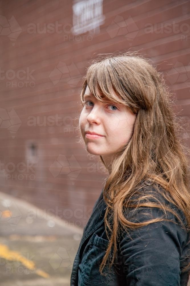 Young teen girl with a fringe in an alleyway looking sad - Australian Stock Image