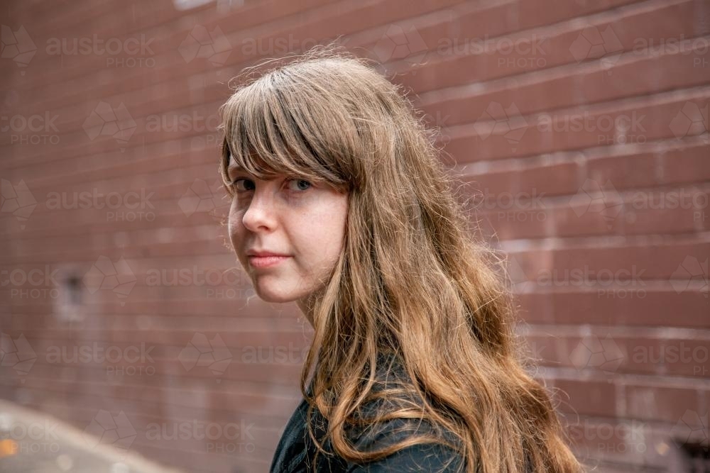 Young teen girl with a fringe in an alleyway looking sad - Australian Stock Image