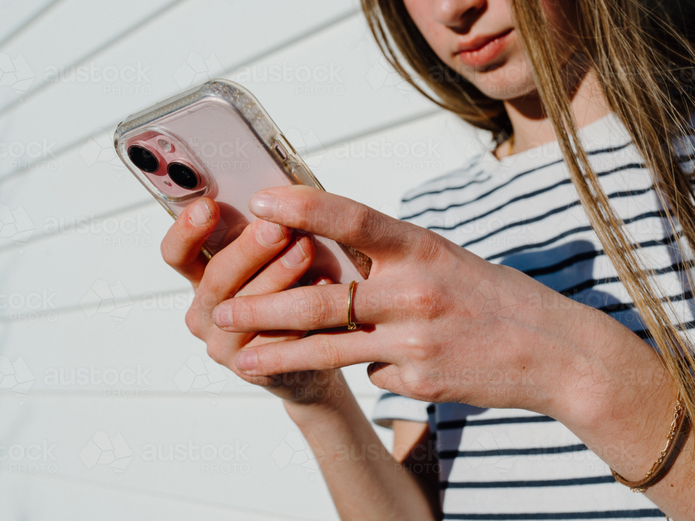 Young teenage girl holding a mobile device. - Australian Stock Image