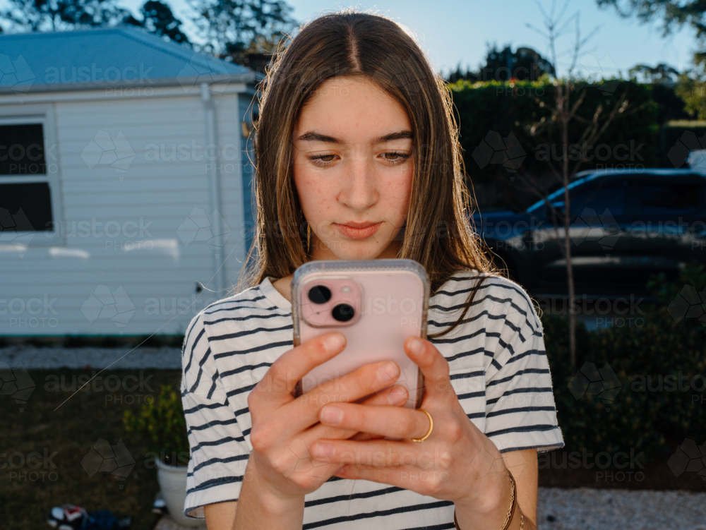 Young teenage girl holding a mobile device. - Australian Stock Image