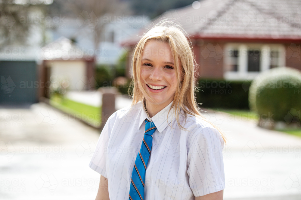 Young teenage girl in school uniform standing on the roadside - Australian Stock Image