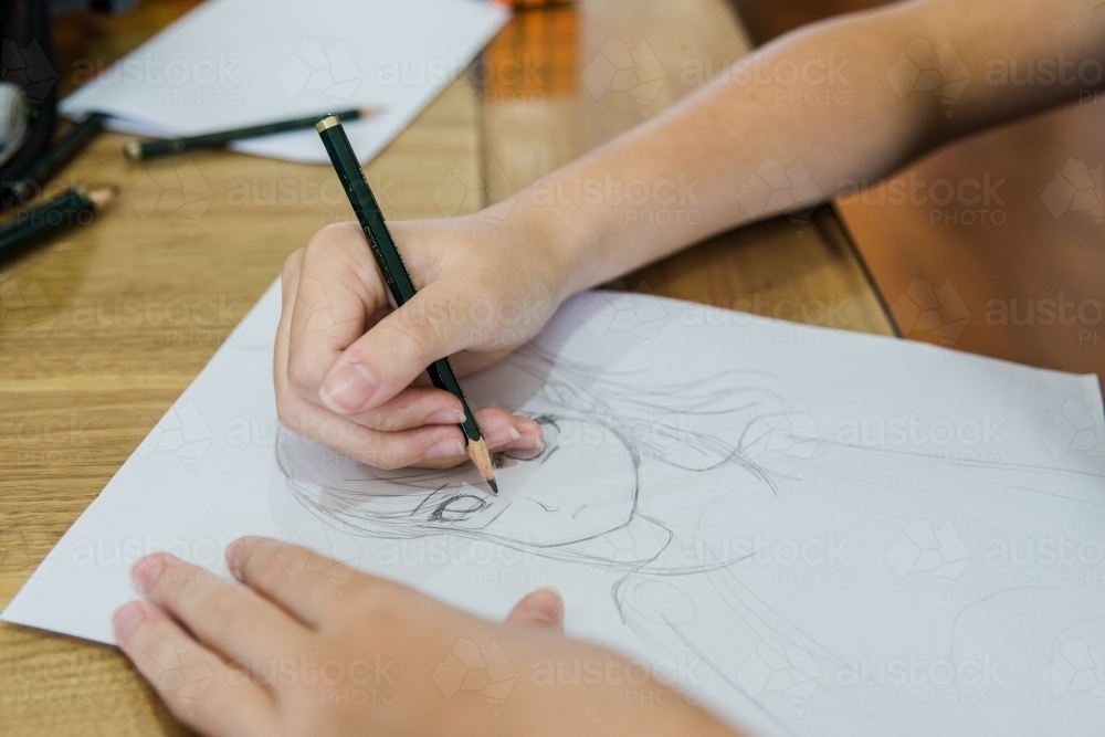 Young teenage girl is drawing Manga creating artwork - Australian Stock Image