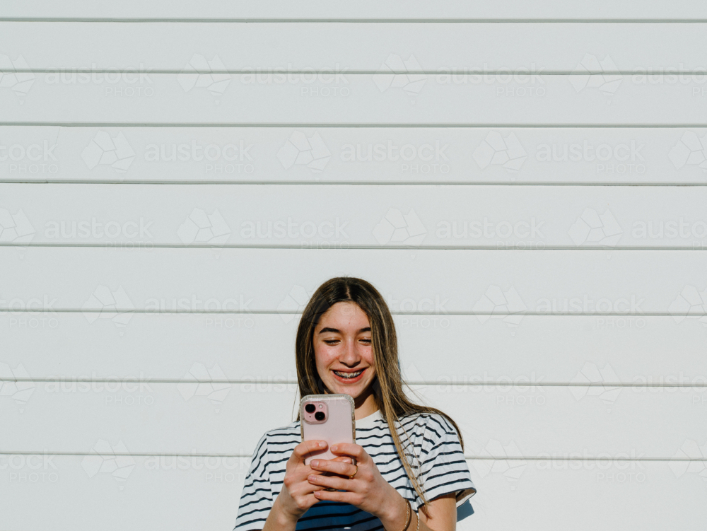 Young teenage girl taking selfies using her mobile device. - Australian Stock Image